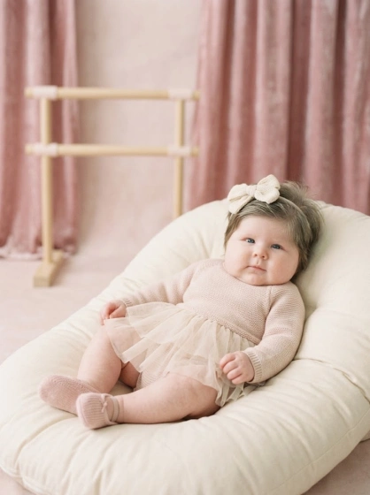 Baby girl in a soft ballerina-inspired outfit with a pastel ballet studio backdrop