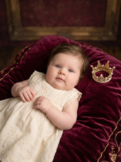 Elegant baby girl portrait with a soft velvet blanket and tiny crown prop placed nearby